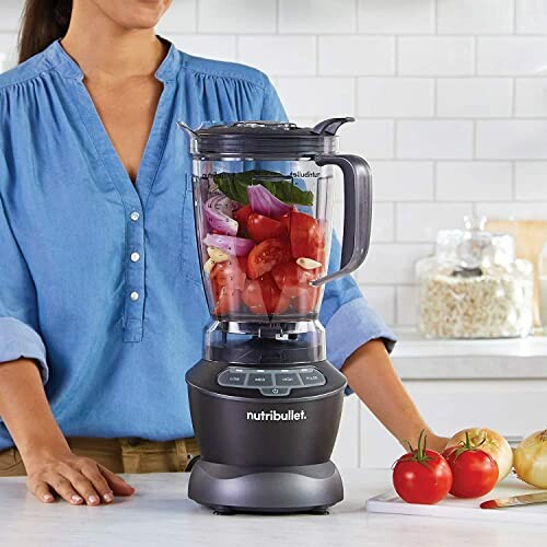 Person with a NutriBullet blender filled with vegetables on a kitchen counter.